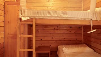 Un lit superposé avec une échelle, des murs en bois et une petite table.