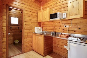 Eine kleine Küche mit Holzwänden, einer Mikrowelle, einem Spülbecken und einem kleinen Kühlschrank.