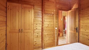 Una habitación de madera con una cama, un armario y una puerta que da a otra habitación.
