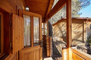 A wooden cabin with a porch, a door with a window, and a ladder leading to a deck. - Country House 'Cabaña De Madera 5' with Mountain View, Shared Pool and Air Conditioning (Hornos)