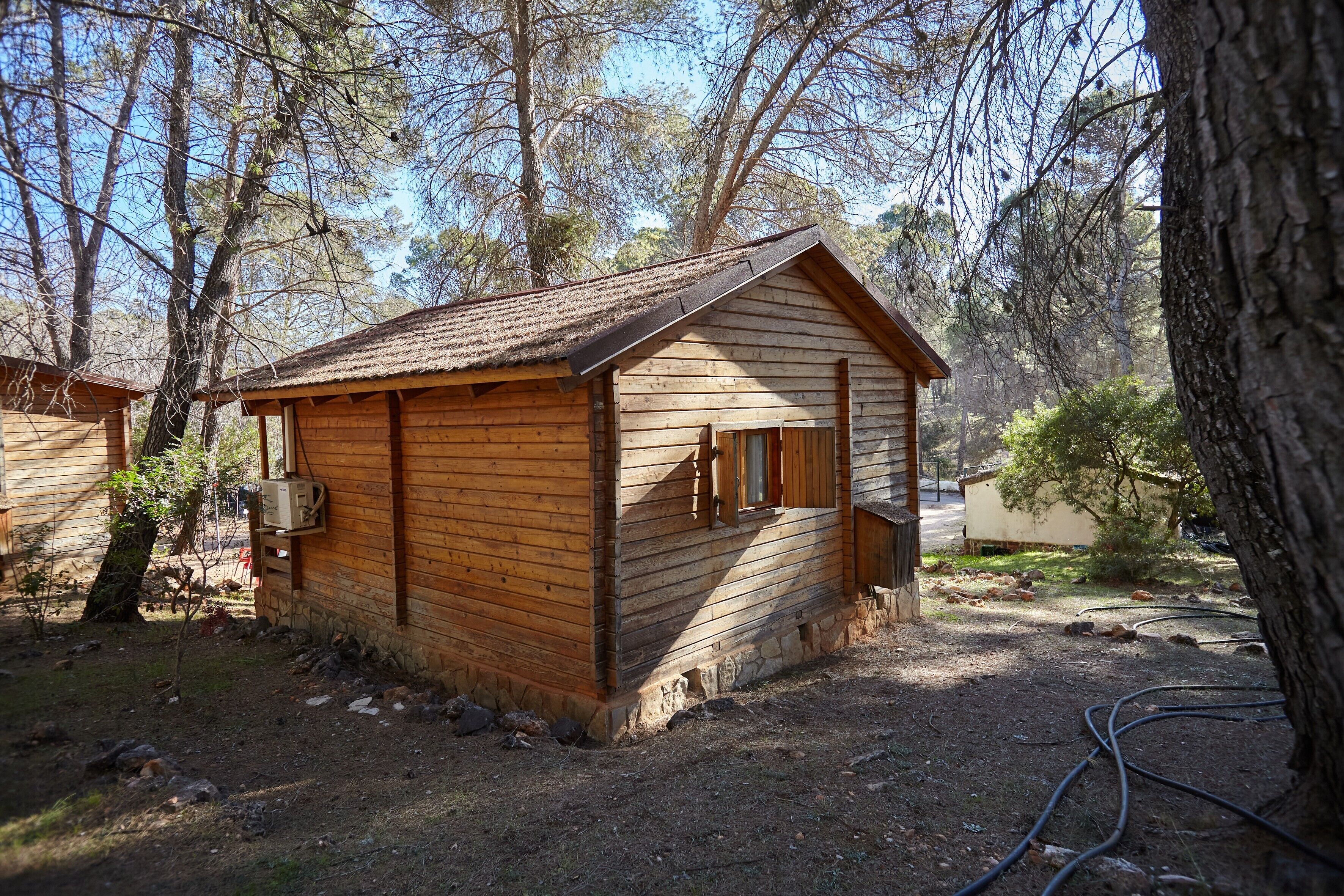 Una cabaña de madera con techo a dos aguas, un porche pequeño y una ventana.