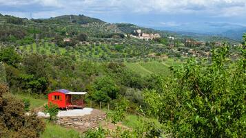 A red building with a white roof, surrounded by lush greenery and hills.