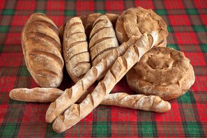 A variety of breads on a plaid tablecloth.