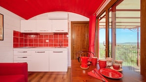 Een keuken met witte kastjes, een backsplash van rode tegels, en een eethoek met een tafel gedekt voor twee personen.