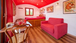Een kamer met een rode plafond, een bed met een rode matras, een rode bank, een houten tafel met stoelen, en ingelijste foto's aan de wanden.
