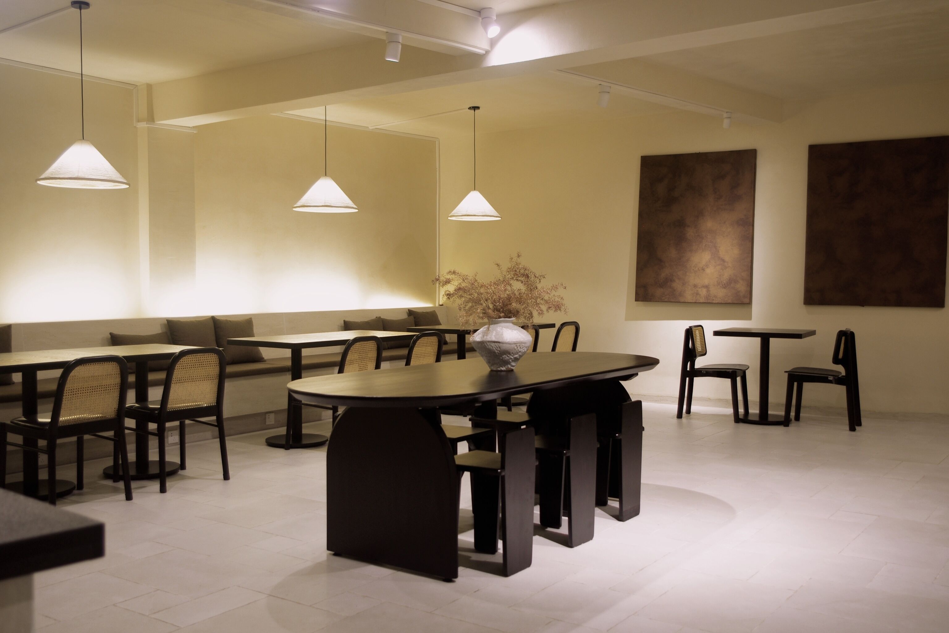 A modern dining area with a central table, surrounding chairs, and pendant lighting.