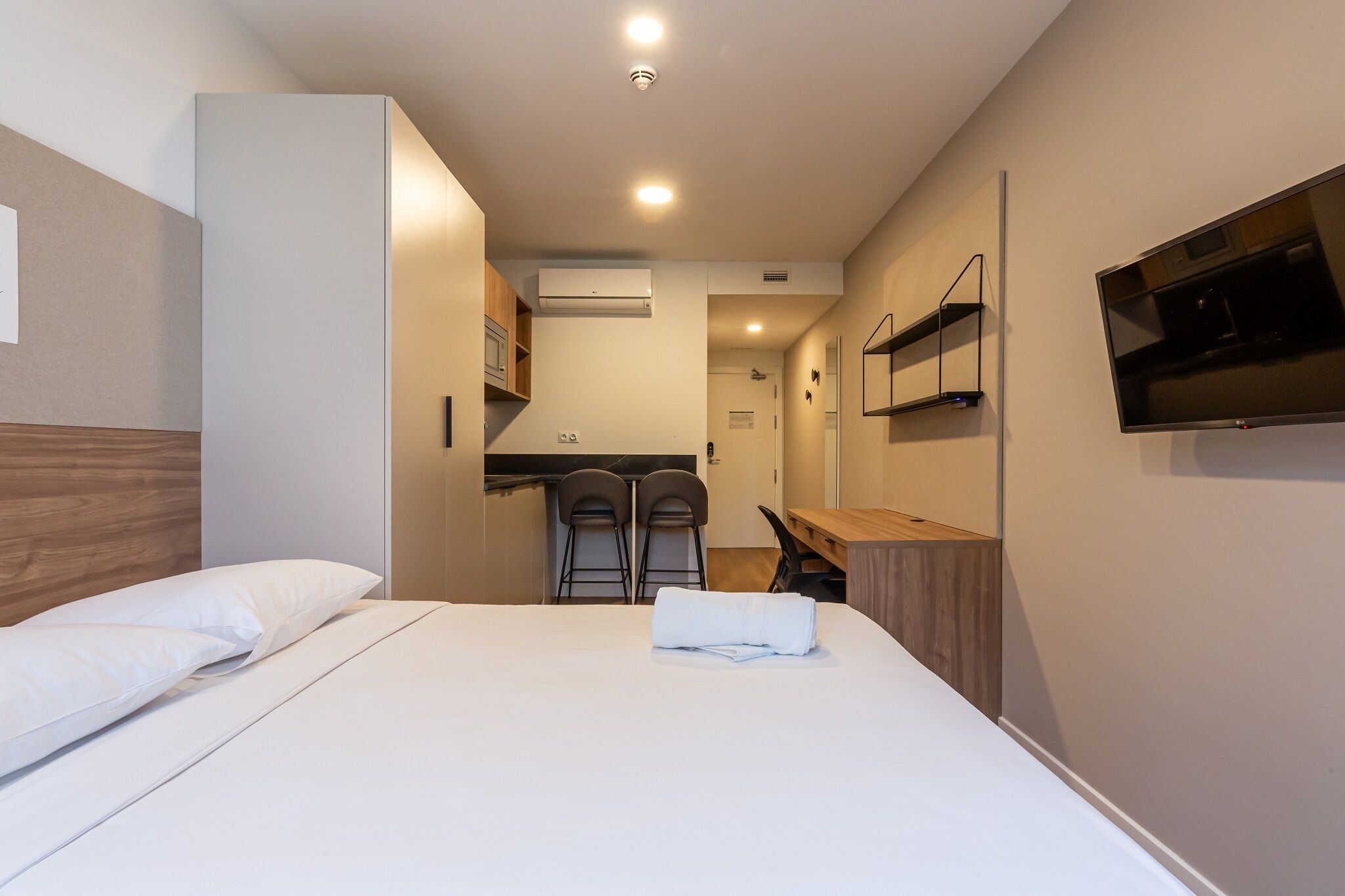 Une chambre d’hôtel équipée d’un lit, de deux chaises, d’un bureau, d’une télévision et d’un appareil de climatisation.
