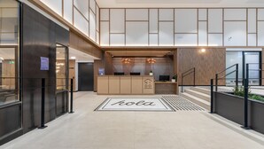 Moderni hotellin aula, jossa on vastaanottotiski, portaikko ja kyltti, jossa lukee ”Kola”.