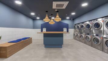 Una lavandería moderna con mostrador central, varias lavadoras y una zona de estar.