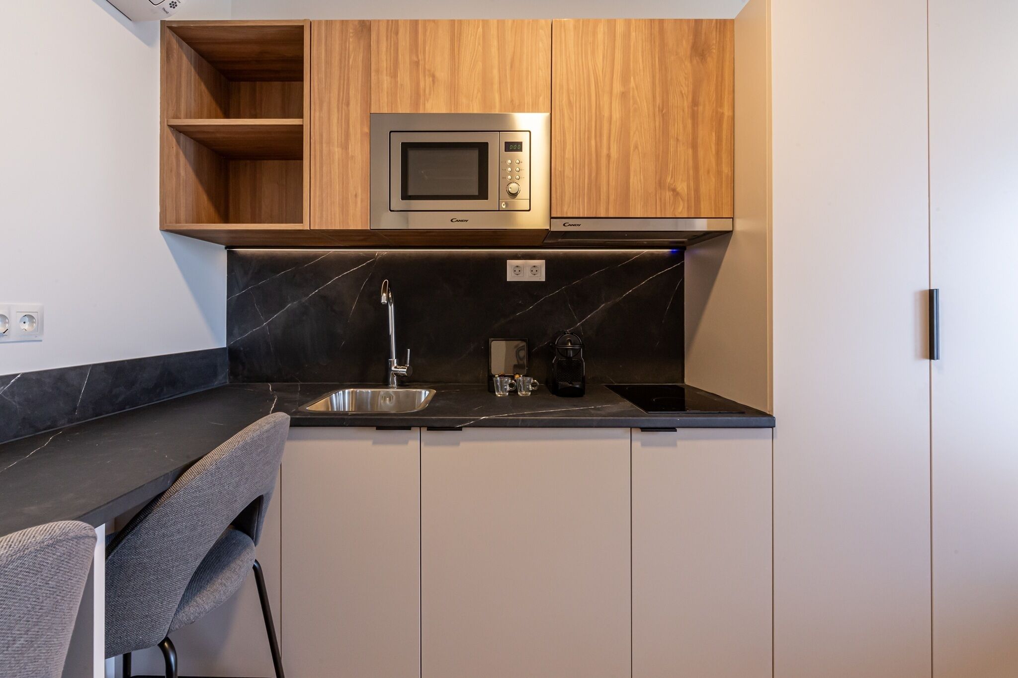 Cocina compacta con microondas, lavamanos y cafetera.