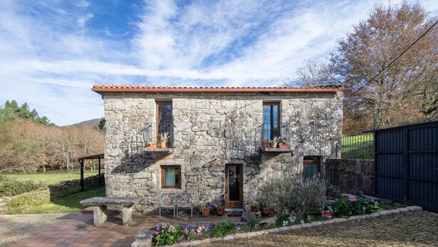 A stone house with a tiled roof, a small porch with a bench, and potted plants. - Rural House 'Chan Da Ra' with Mountain Views, Private Pool and Private Terrace (A Lama)