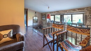 A room with a sofa, patterned chairs, a stone wall, and a view through a window. - Rural House 'Chan Da Ra' with Mountain Views, Private Pool and Private Terrace (A Lama)