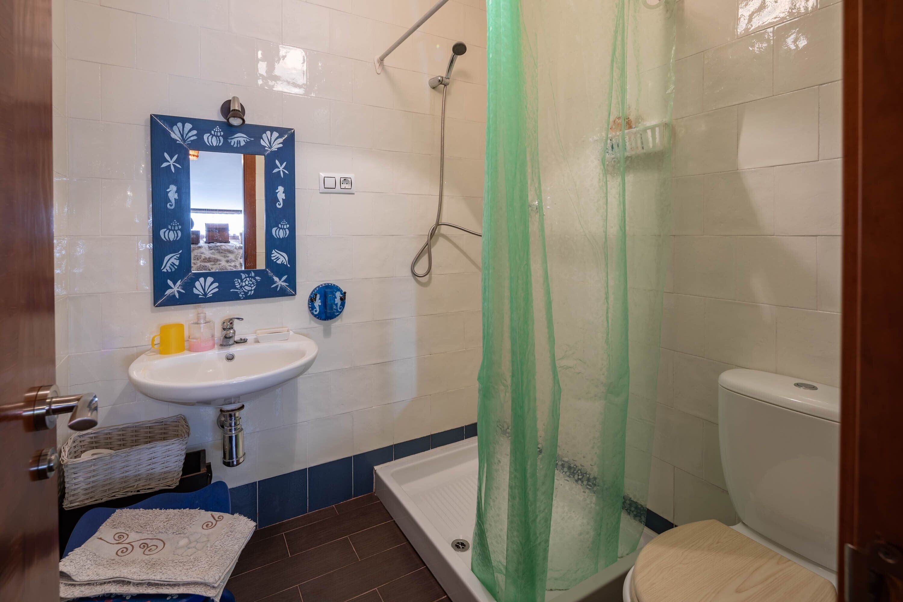 A bathroom with a white sink, mirror, shower, and toilet.