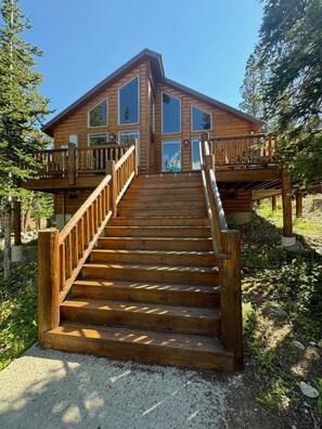 Une cabane en bois avec un escalier menant à une terrasse.