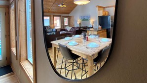 A dining area with a wooden table set for four, a ceiling fan, and a large mirror reflecting the room. - Hot Tub, Mtn Views & Starlink WiFi - Wildlife on Site, Pet-Friendly (Fairplay)