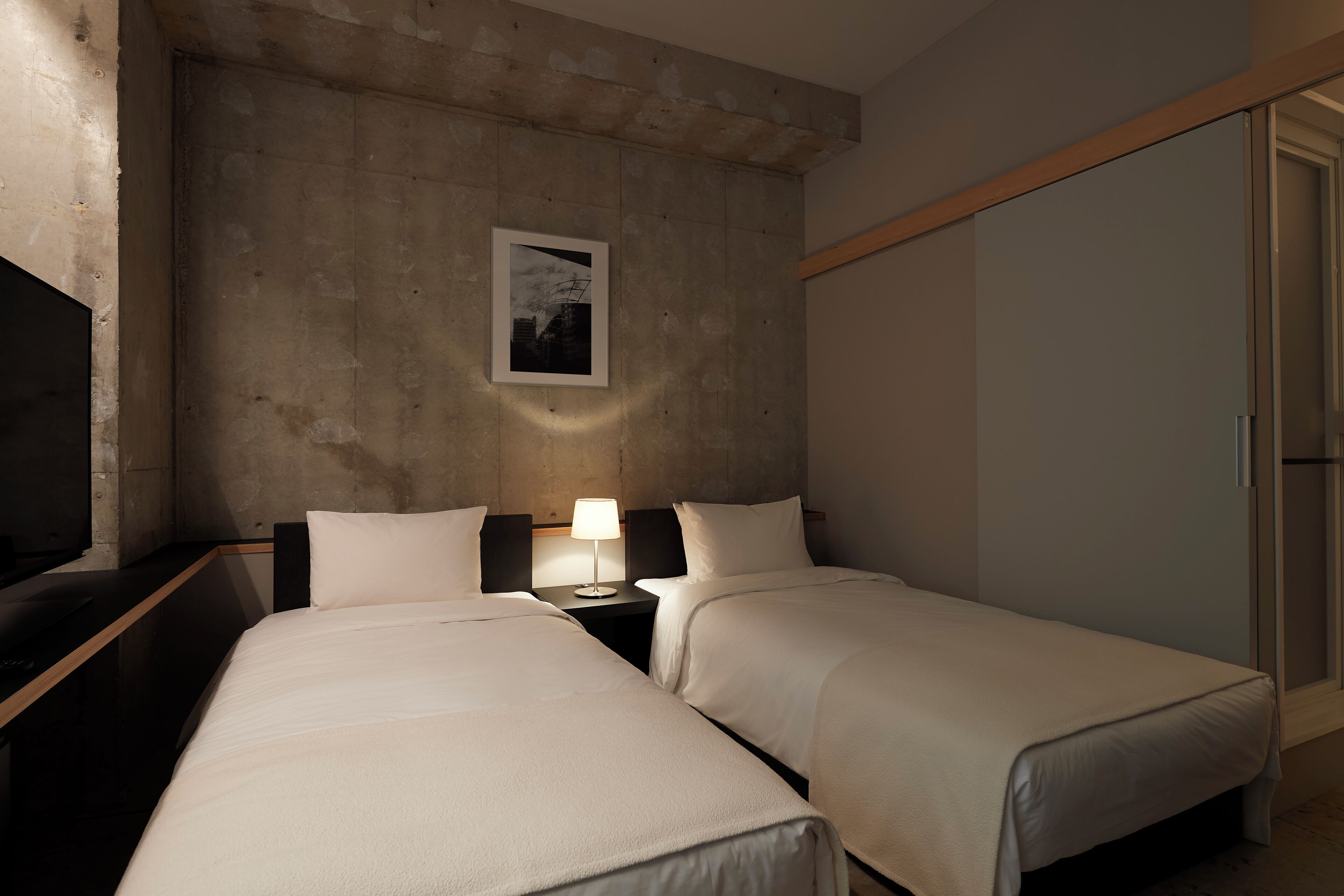 Habitación de hotel con dos camas, televisión, lámpara y un cuadro en la pared.