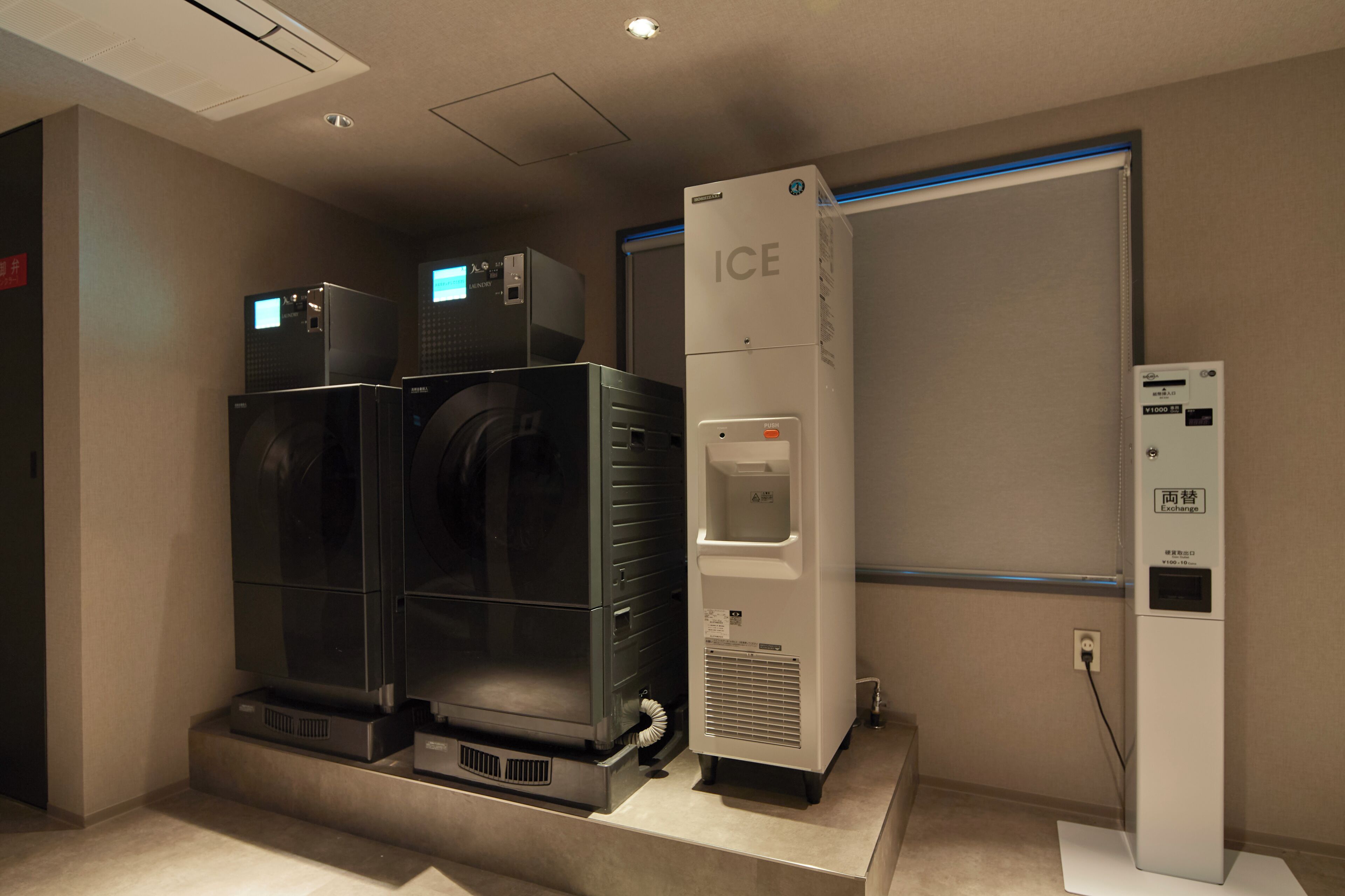 Un espace buanderie équipé de deux grandes machines à laver et d’un distributeur d’eau.