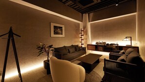 Ein modernes Wohnzimmer mit einer Couch, Sesseln, einem Couchtisch und einem Bücherregal.