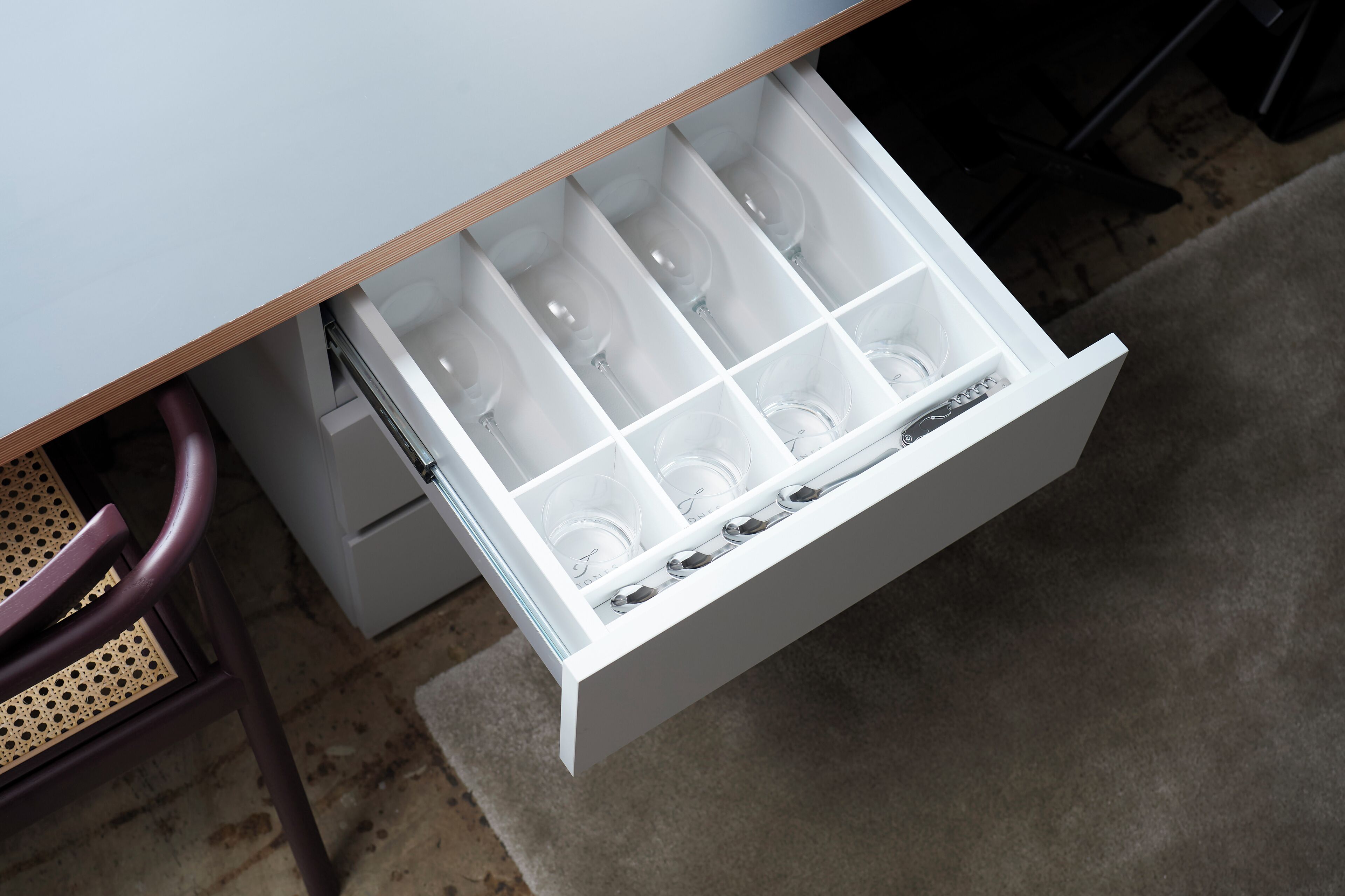 A drawer with multiple compartments, some containing clear plastic cups.