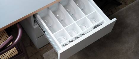 A drawer with multiple compartments, some containing clear plastic cups.