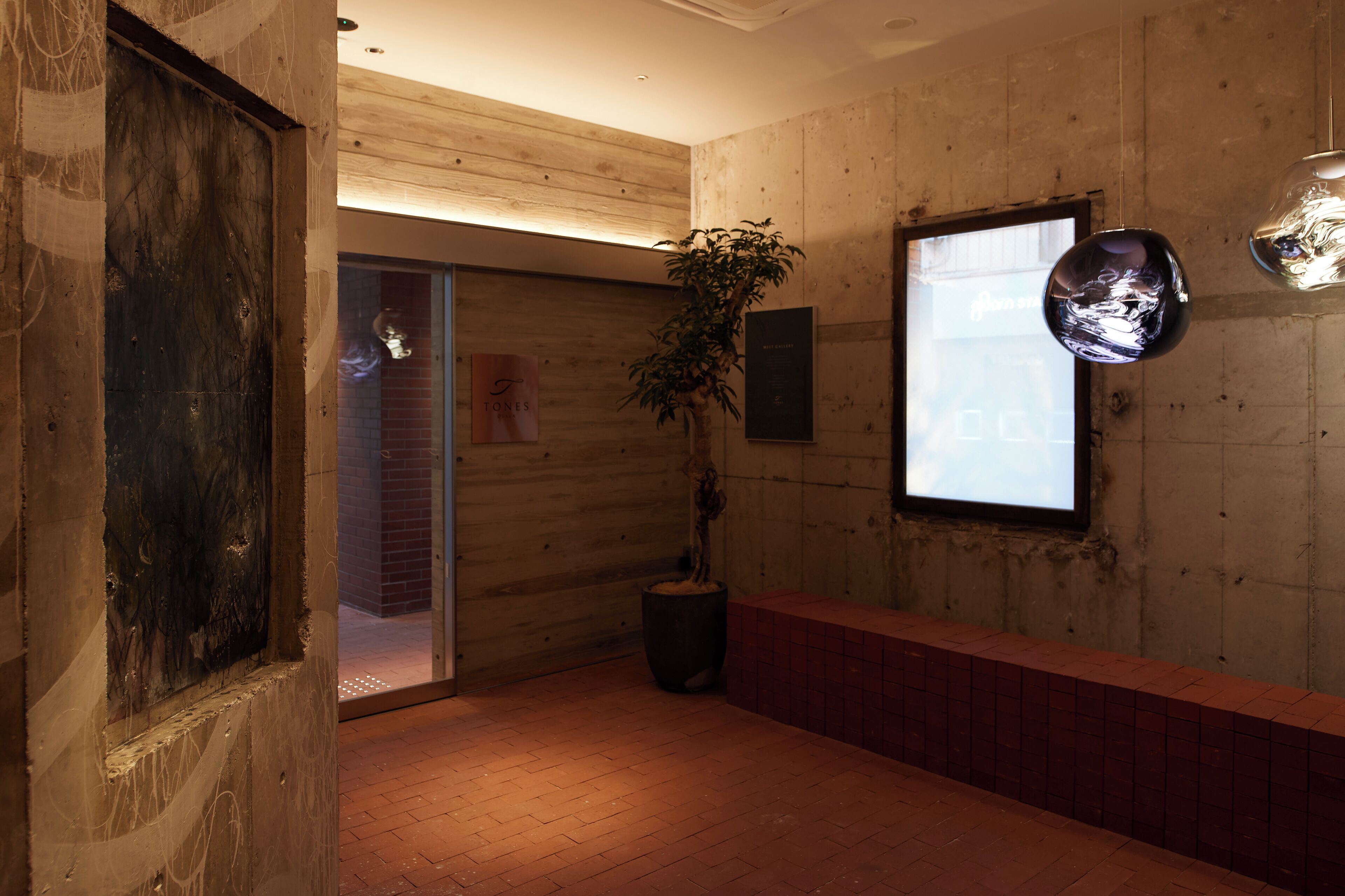 Un interior de madera con una planta en maceta, un aplique de pared y una puerta que da a otra habitación.