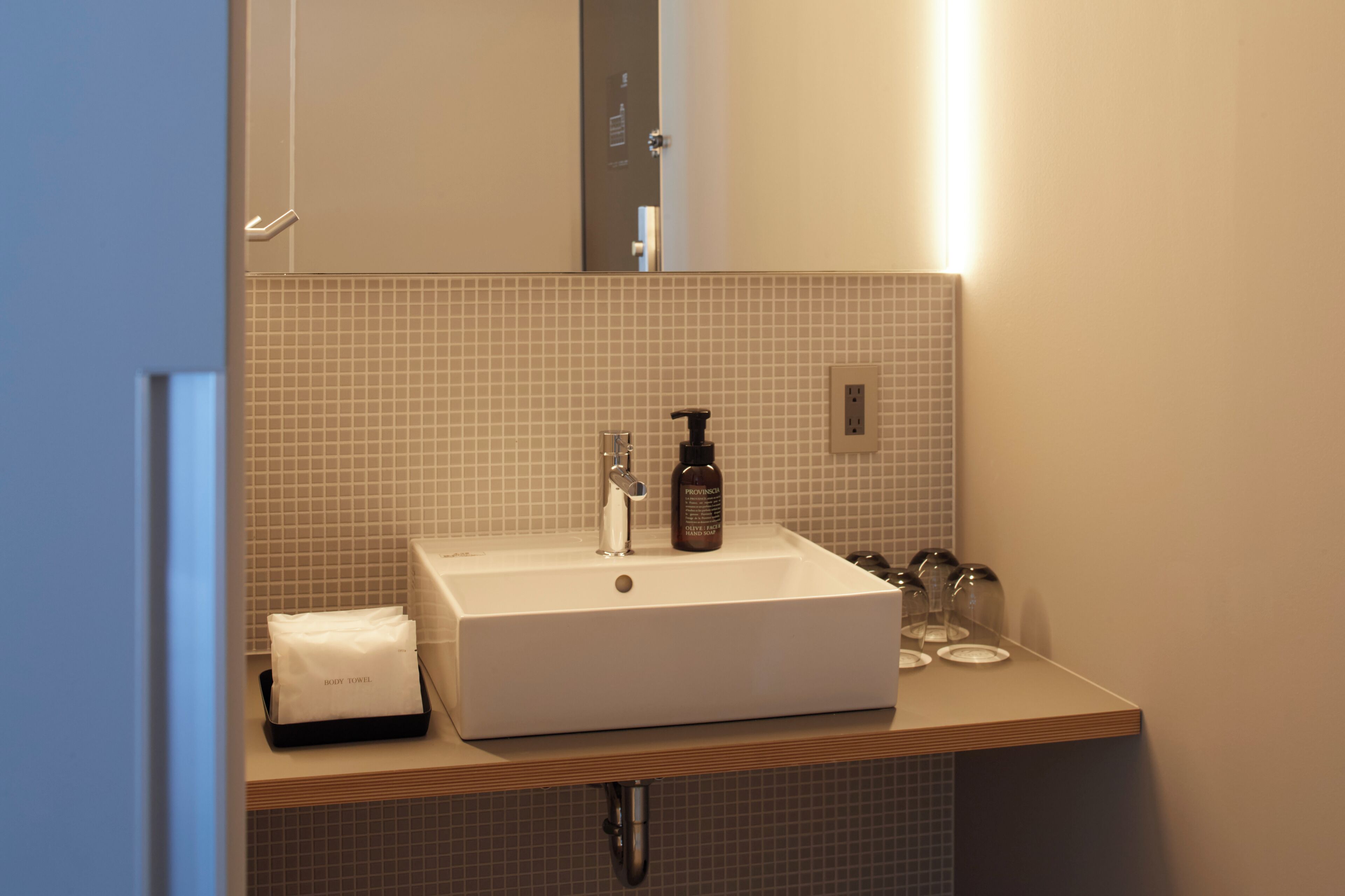 A bathroom with a white sink, a bottle of shampoo, and a towel on the counter.