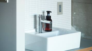 A white bathroom sink with a modern faucet and a bottle of olive oil hand soap.
