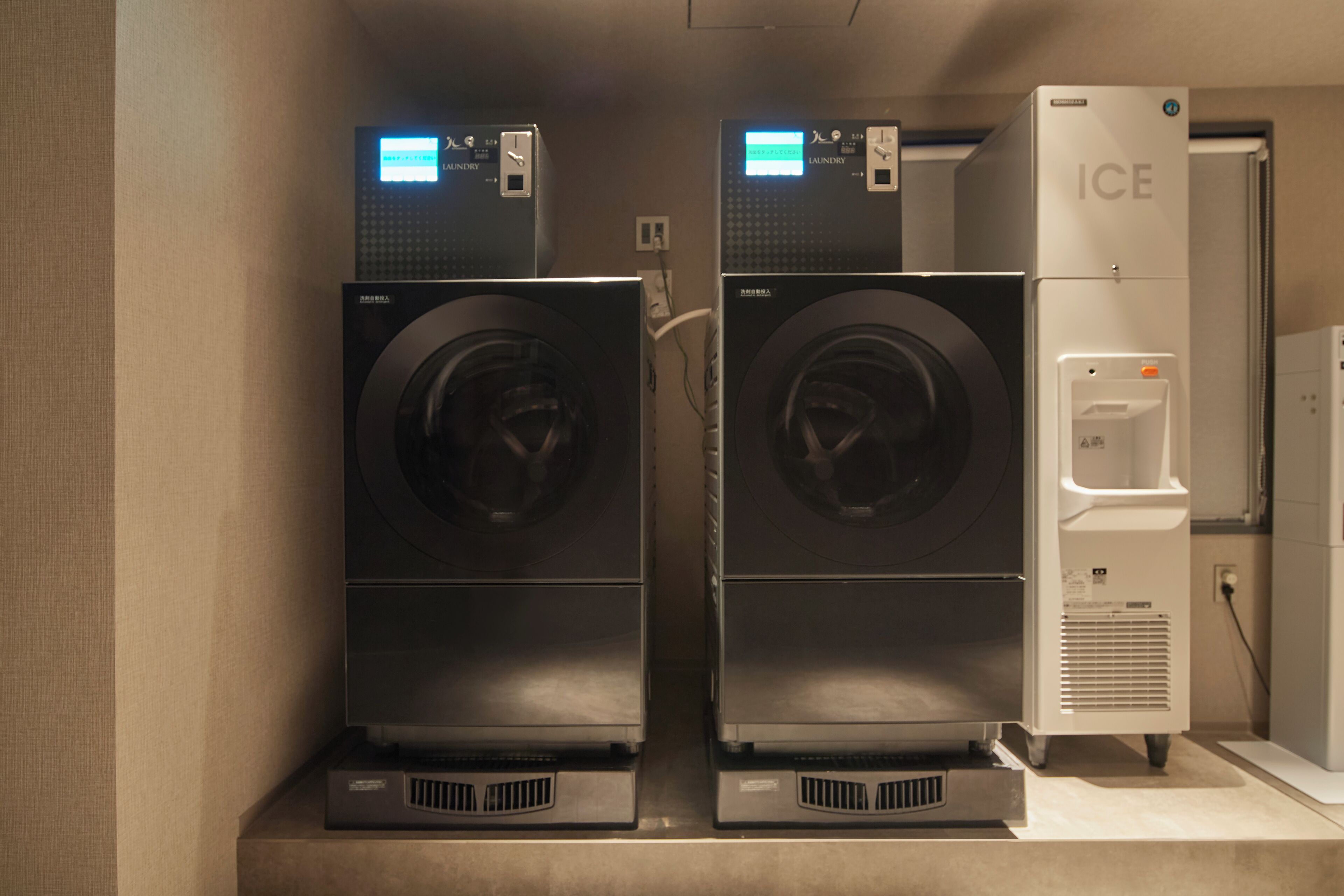 Two front-loading washers and a water dispenser in a laundry room.