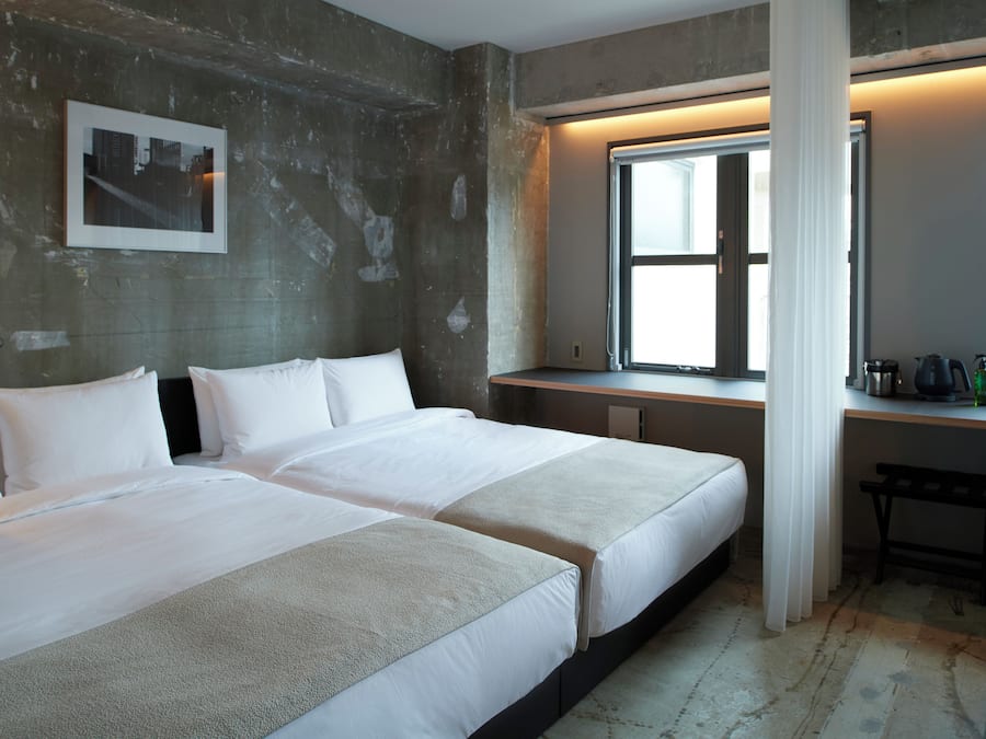 Une chambre d’hôtel avec deux lits, un bureau et une grande fenêtre.