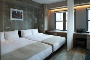 Une chambre d’hôtel avec deux lits, un bureau et une grande fenêtre.