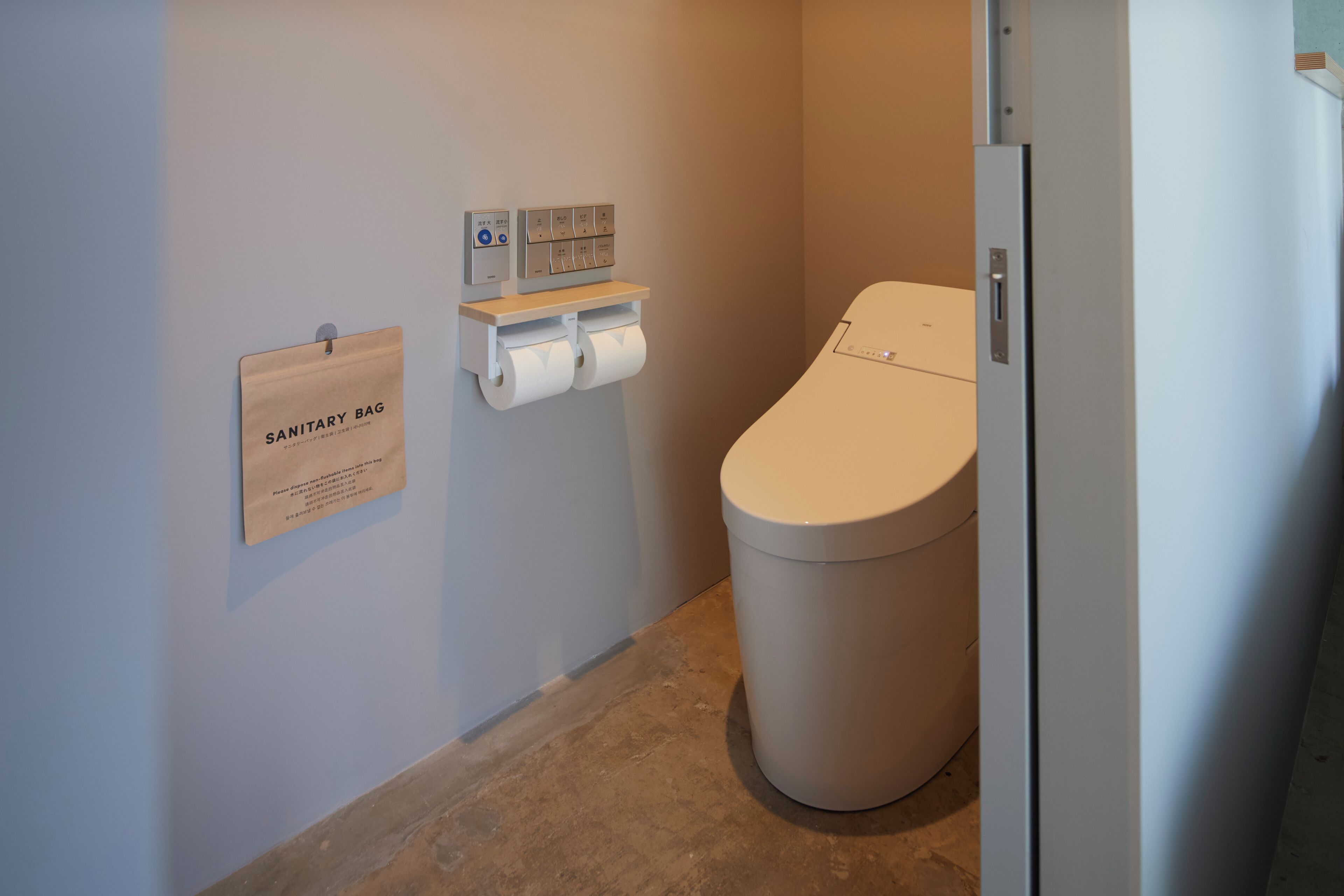 Une salle de bain équipée de toilettes, d’un distributeur de sacs d’hygiène et d’un panneau de commande fixé au mur.