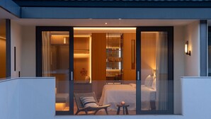 A modern hotel room with a glass door leading to a balcony, a bed, a chair, and a small table with a fruit. - Papman Hotel (Kunming)