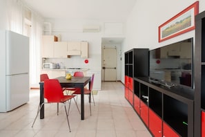 A modern kitchen with a dining area, white cabinets, a black and red cabinet, and a microwave.