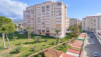 Un edificio residencial de varios pisos con un patio central, rodeado de vegetación y palmeras.