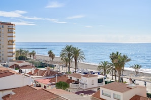 Un pueblo costero con edificios, una playa y palmeras.