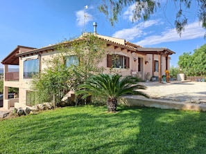 A two-story house with a balcony, a water tank on the roof, and a well-maintained lawn. - Villa 'Il Rifugio Della Quiete' with Mountain View, Wi-Fi and Air Conditioning (Scicli)