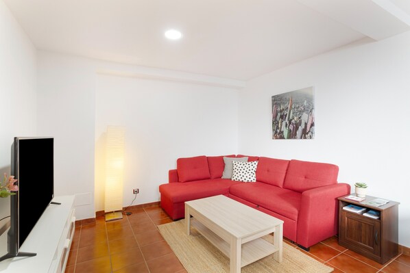 A living room with a red sofa, a coffee table, a TV, a lamp, and a cabinet.