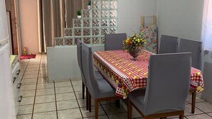 A dining area with a table set for four, surrounded by chairs, and a decorative wall unit with plants. - Casa Campos do Iguaçu - Perto de Tudo (Foz do Iguaçu)