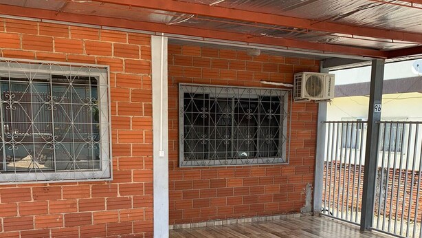 An empty room with a wooden floor, brick walls, and metal-framed windows. - Casa Campos do Iguaçu - Perto de Tudo (Foz do Iguaçu)