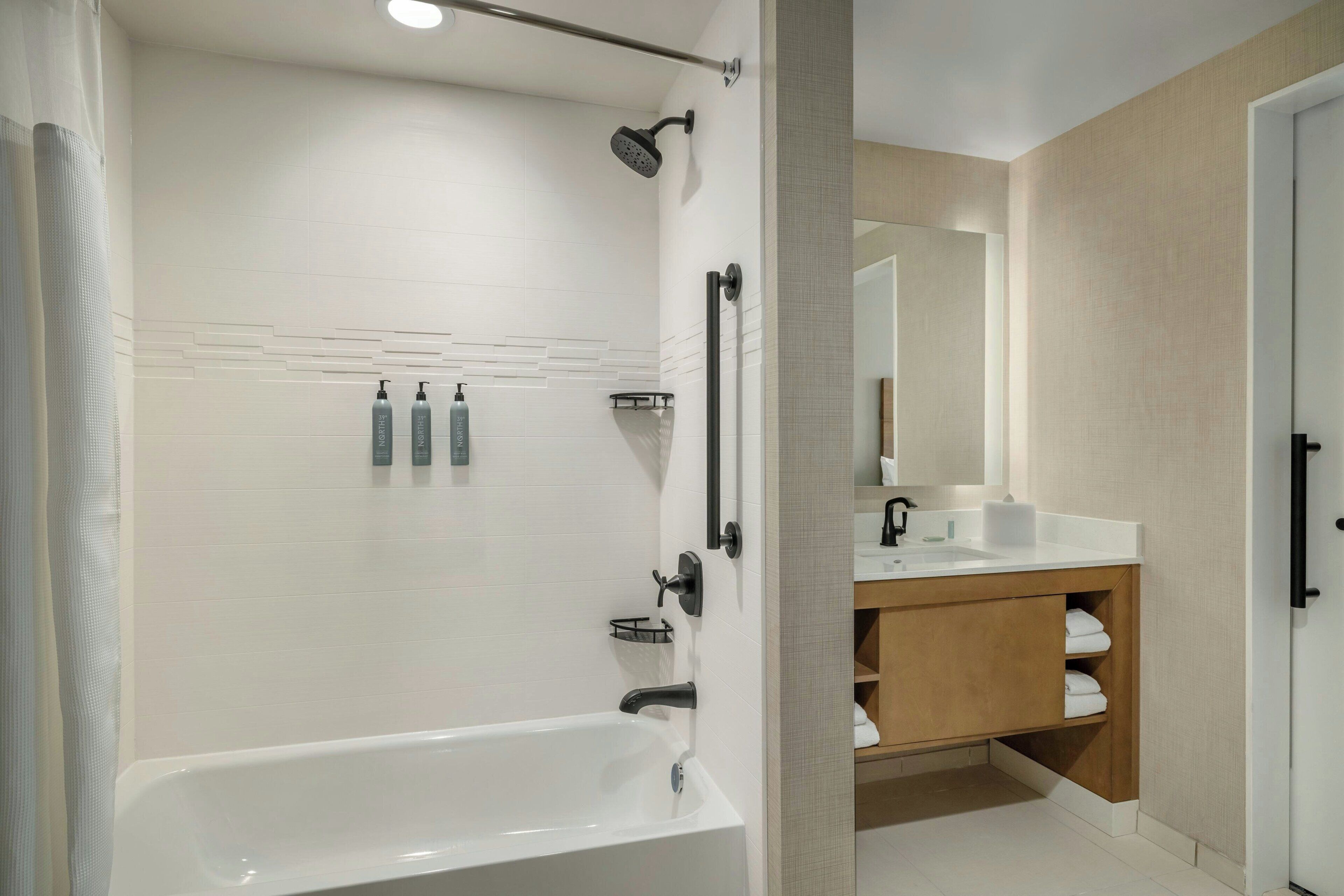 A modern bathroom with a bathtub, a shower, and a vanity with a mirror.
