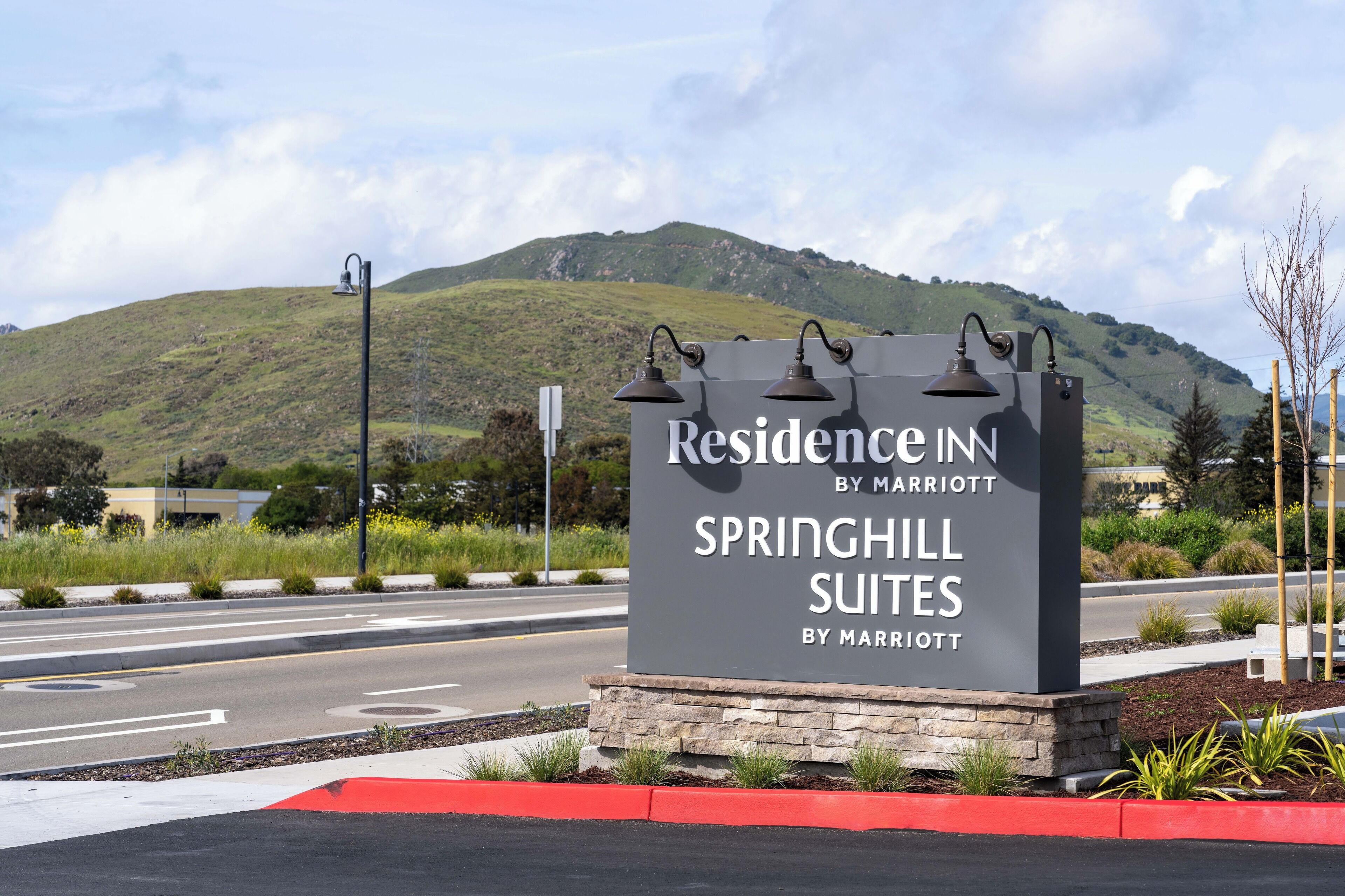 A sign for Springhill Suites by Marriott with a view of a hilly landscape in the background.