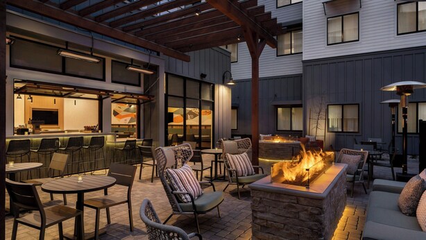 An outdoor patio area with seating, a bar, and a fire feature.