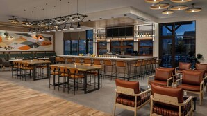 A modern restaurant with a bar area, wooden flooring, and contemporary lighting fixtures.