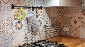 A kitchen with patterned tiles, a gas stove, and hanging kitchen utensils. - Apartment 'Le Terrazze Sul Mare - Capo' with Sea View, Private Terrace and Wi-Fi (Cefalù)