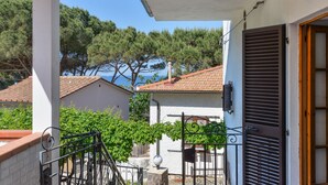 A balcony with a view of a building and trees, a metal gate, and a door with shutters. - Holiday Home 'Innamorata Mare' with Sea View, Private Terrace and Wi-Fi (Capoliveri)