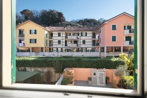 Una hilera de edificios de varios pisos con balcones, un pequeño jardín y vistas a una colina.
