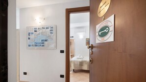 Une chambre d’hôtel avec un lit, une carte accrochée au mur et une porte ornée d’une pancarte de bienvenue.