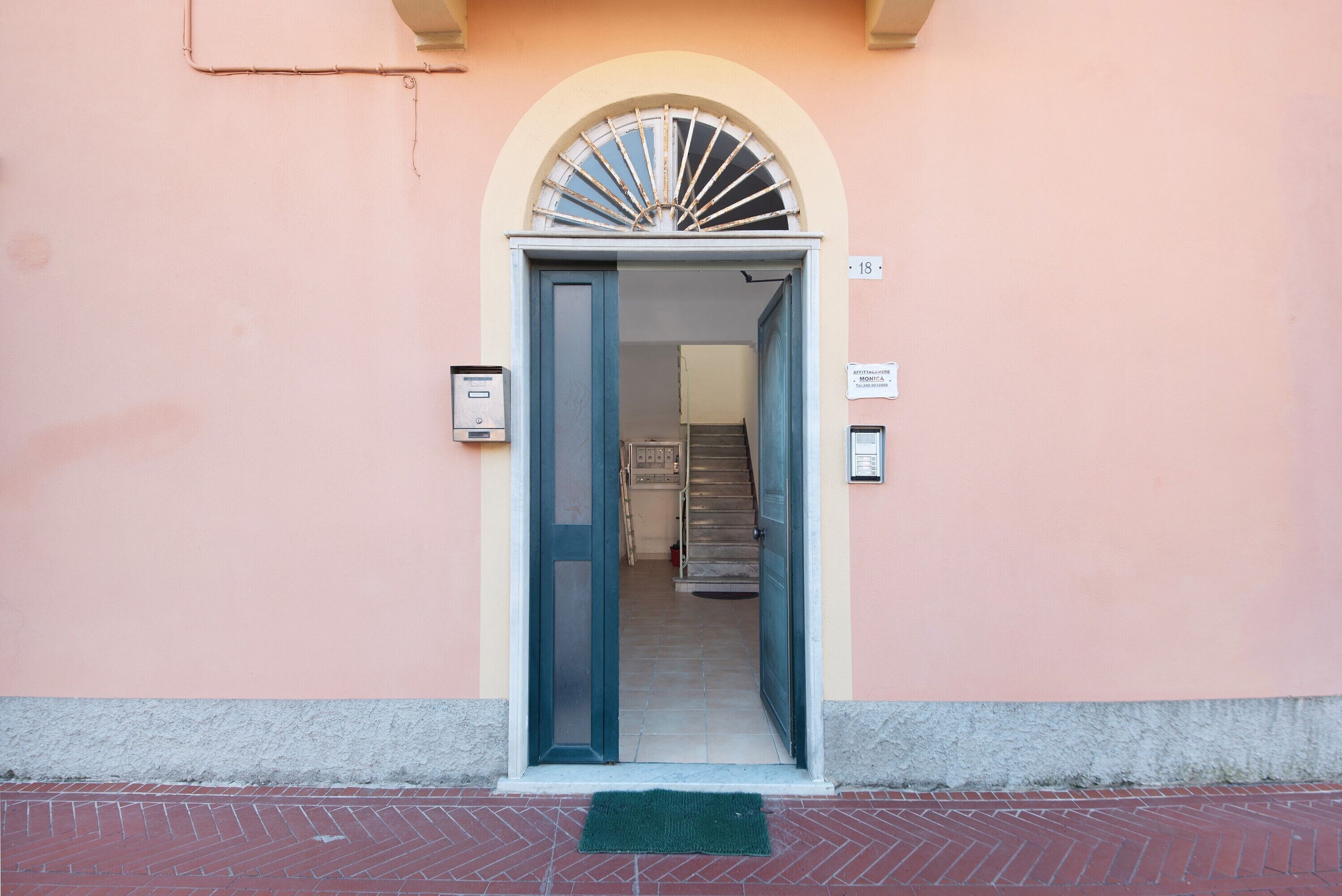 L'ingresso di un edificio con una porta, una scala e un cartello a parete.