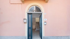 Une entrée d’immeuble avec une porte, un escalier et une enseigne fixée au mur.