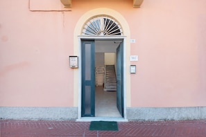A building entrance with a door, a staircase, and a wall-mounted sign.